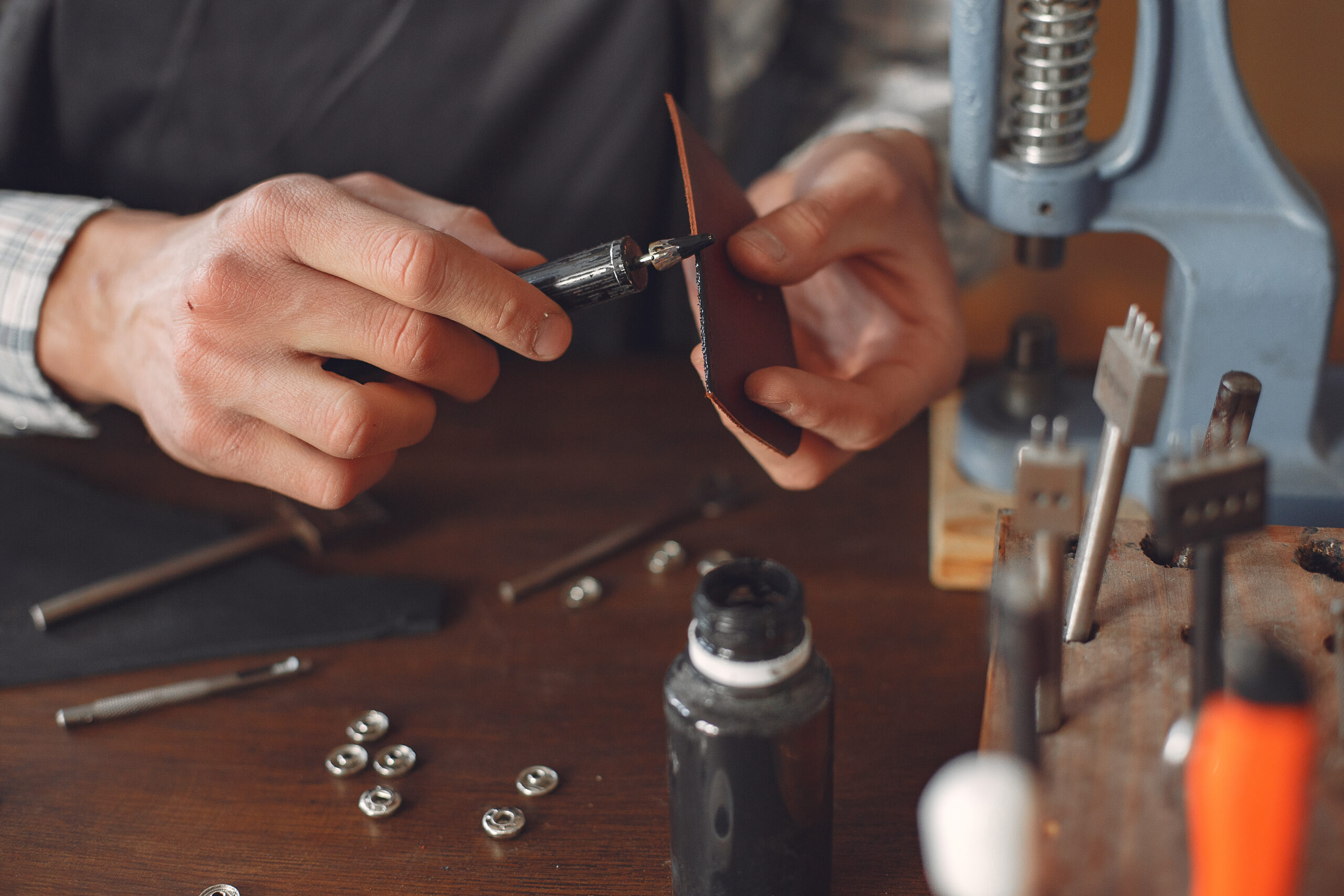 Man working with leather. Professional makes a holes. Man upaints the leather.